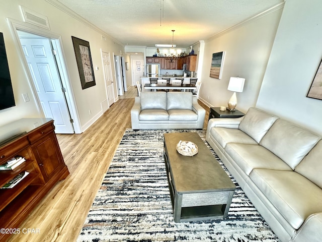 17643 Front Beach Rd Unit 1806, Panama City Beach, FL 32413 - living room featuring a notable chandelier, a textured ceiling, light wood-style floors, and crown molding
