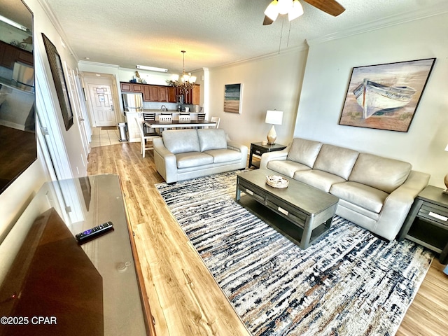 17643 Front Beach Rd Unit 1806, Panama City Beach, FL 32413 - living area featuring ornamental molding, light wood-style floors, a textured ceiling, and ceiling fan with notable chandelier