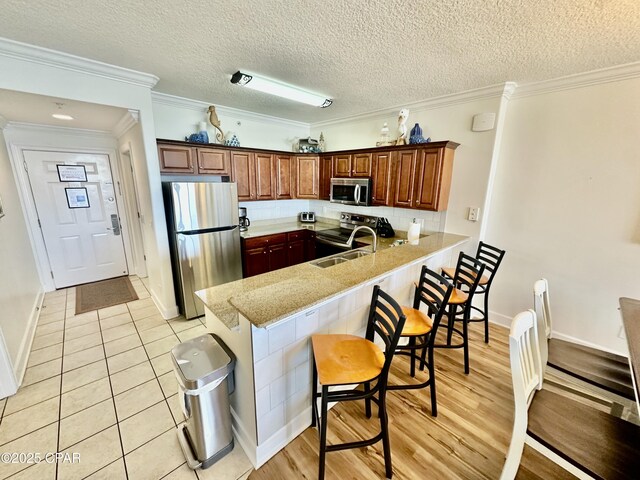 17643 Front Beach Rd Unit 1806, Panama City Beach, FL 32413 - kitchen with stainless steel appliances, a peninsula, a sink, baseboards, and a breakfast bar