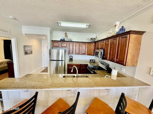 kitchen with kitchen peninsula, stainless steel appliances, a textured ceiling, and sink