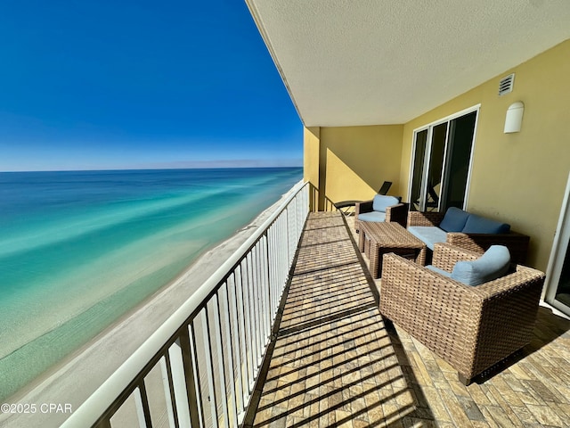 balcony with a water view and a view of the beach