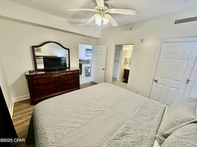 bedroom with ceiling fan, light wood-type flooring, and connected bathroom