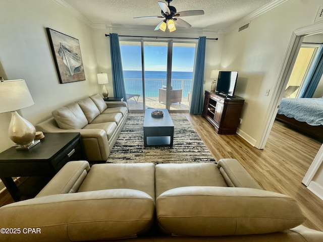 living room with ceiling fan, crown molding, a textured ceiling, and light hardwood / wood-style flooring