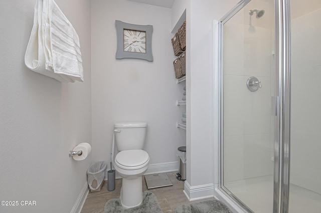 bathroom featuring toilet and a shower with shower door