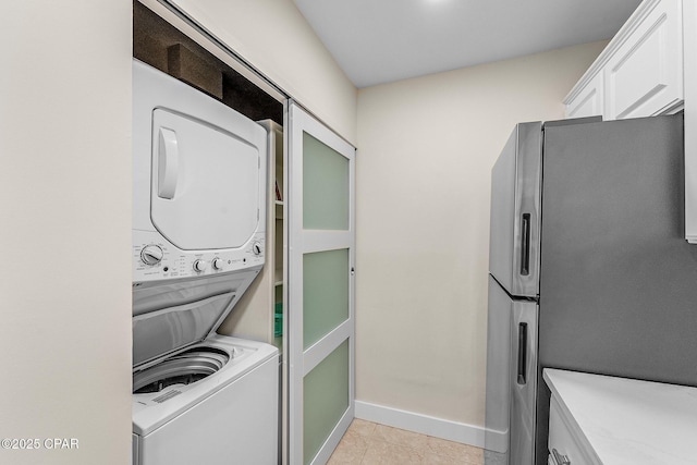 laundry area with stacked washer and clothes dryer and light tile patterned floors