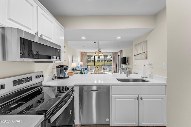 kitchen featuring stainless steel appliances, white cabinetry, hanging light fixtures, and sink