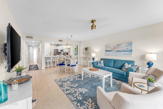 living room featuring ceiling fan with notable chandelier and light tile patterned floors