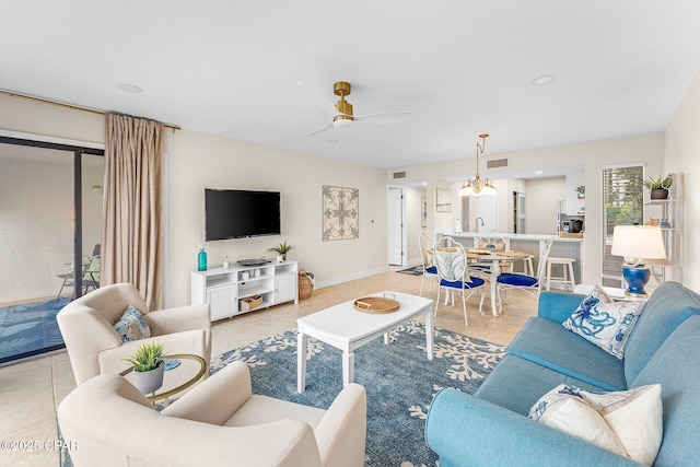 tiled living room with ceiling fan with notable chandelier