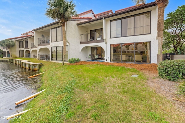 rear view of house featuring a water view and a lawn