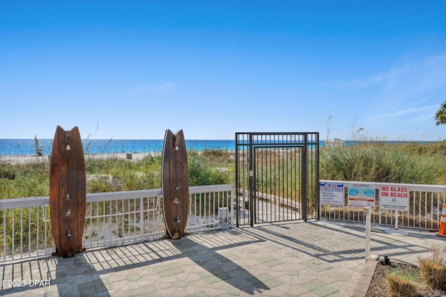 view of gate featuring a view of the beach and a water view