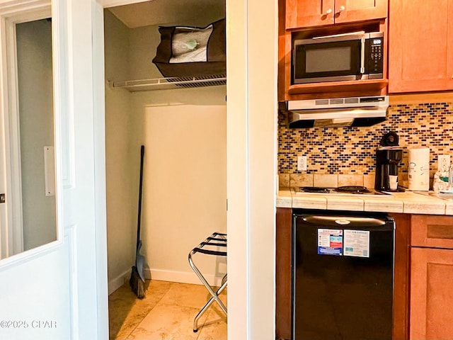 kitchen featuring gas stovetop, tile countertops, light tile patterned floors, and decorative backsplash