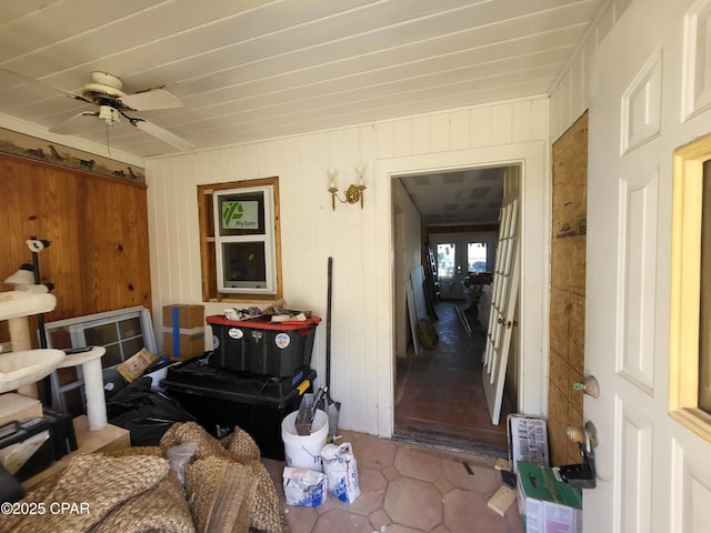 interior space featuring ceiling fan and wood walls