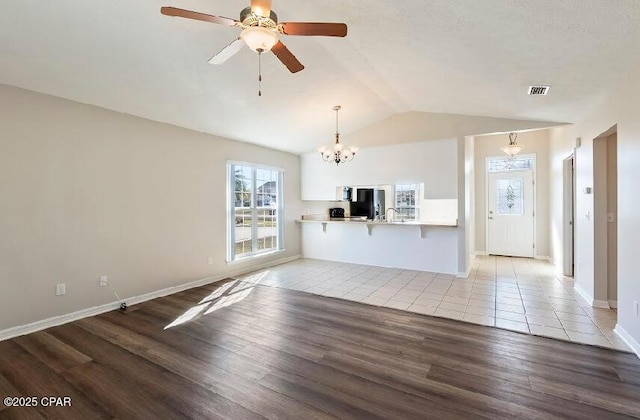 unfurnished living room featuring ceiling fan with notable chandelier, lofted ceiling, light hardwood / wood-style floors, and sink