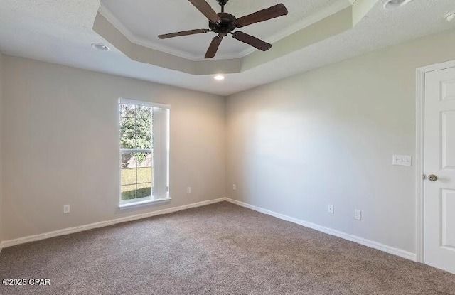 unfurnished room featuring carpet, ceiling fan, a tray ceiling, and ornamental molding