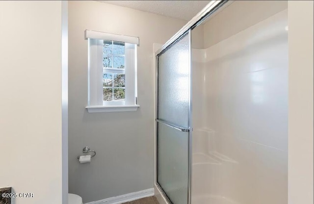 bathroom with a shower with shower door and toilet