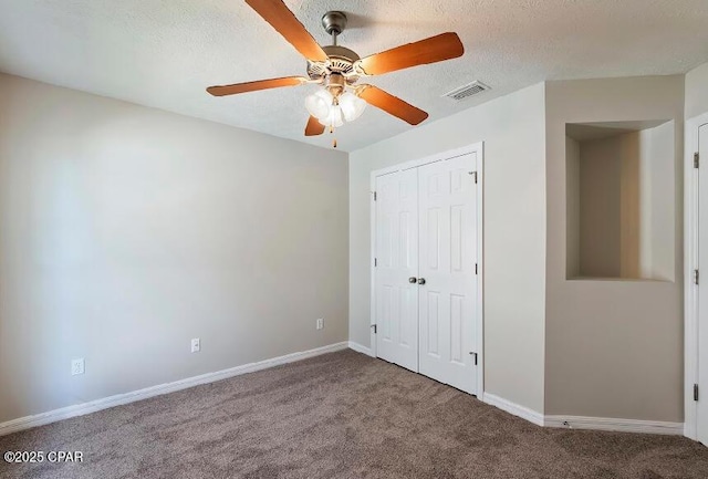 unfurnished bedroom with a textured ceiling, ceiling fan, carpet, and a closet