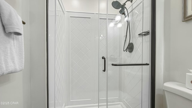 bathroom featuring toilet and a shower with shower door