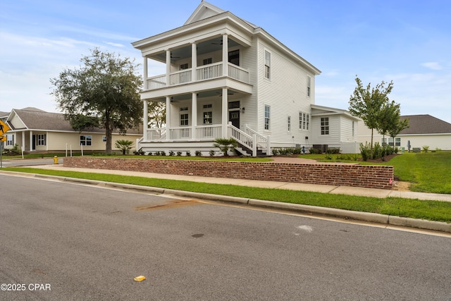 view of front facade with a porch, a balcony, ceiling fan, and a front lawn