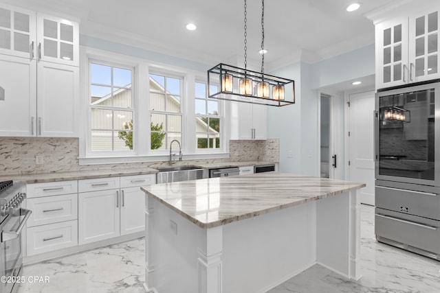 kitchen with sink, white cabinetry, ornamental molding, and a center island