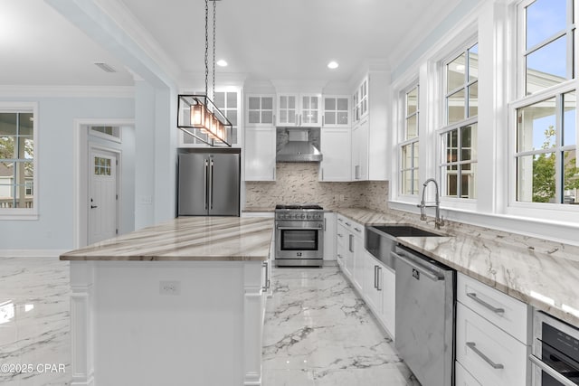 kitchen with high quality appliances, white cabinets, a kitchen island, and wall chimney exhaust hood