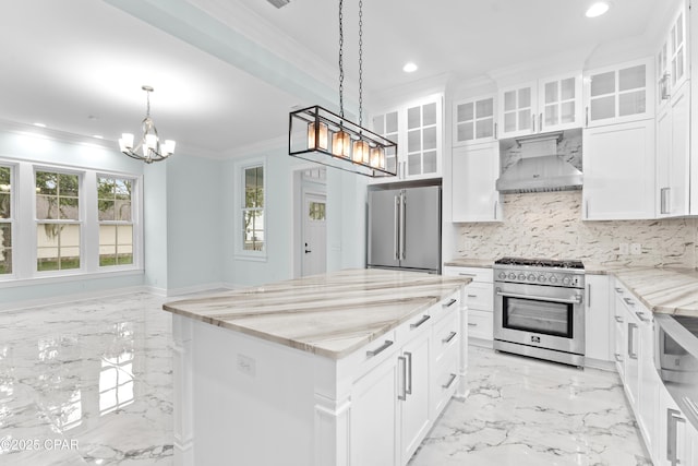 kitchen with white cabinets, a center island, wall chimney exhaust hood, high end appliances, and crown molding