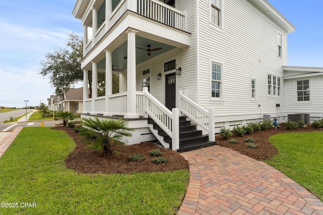 property entrance with a yard, a balcony, covered porch, central AC, and ceiling fan