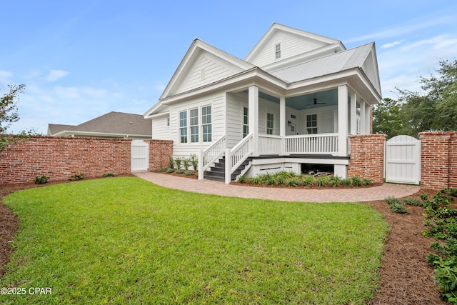 rear view of house featuring covered porch, ceiling fan, and a lawn