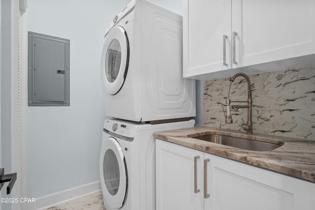 laundry area featuring stacked washer and dryer, sink, electric panel, and cabinets