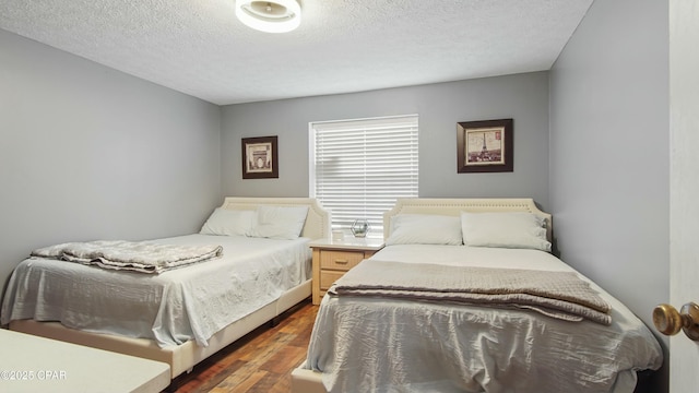 bedroom with a textured ceiling and dark hardwood / wood-style flooring