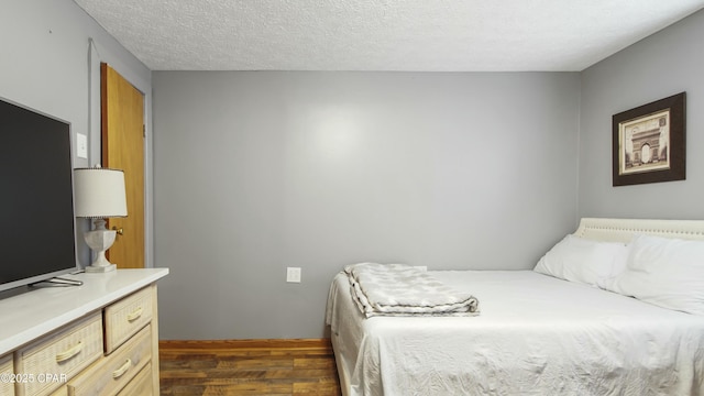 bedroom featuring a textured ceiling and dark hardwood / wood-style floors