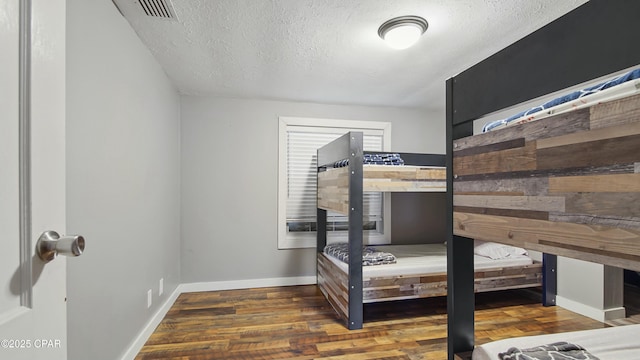 bedroom featuring a textured ceiling and dark hardwood / wood-style flooring