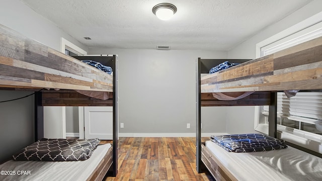 bedroom with a textured ceiling and wood-type flooring