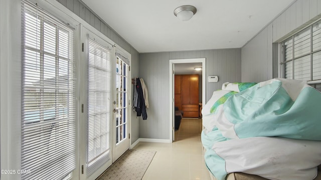 interior space with light tile patterned flooring, french doors, and wooden walls