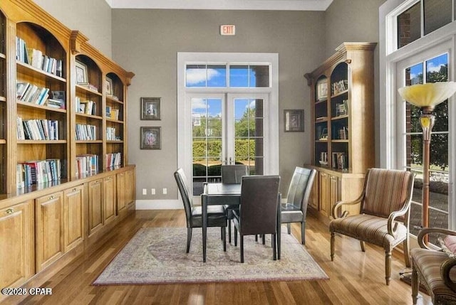 dining area with light hardwood / wood-style floors, french doors, and a high ceiling