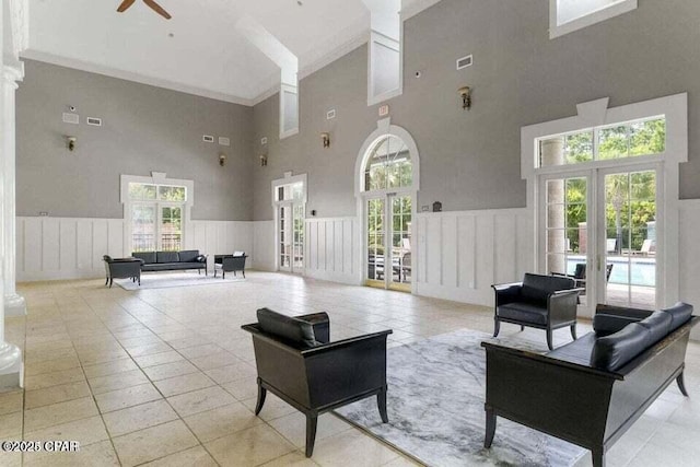 tiled living room with a high ceiling, ceiling fan, french doors, and crown molding