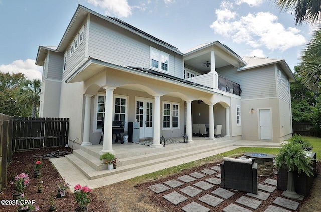 rear view of property featuring a balcony, ceiling fan, and a fire pit