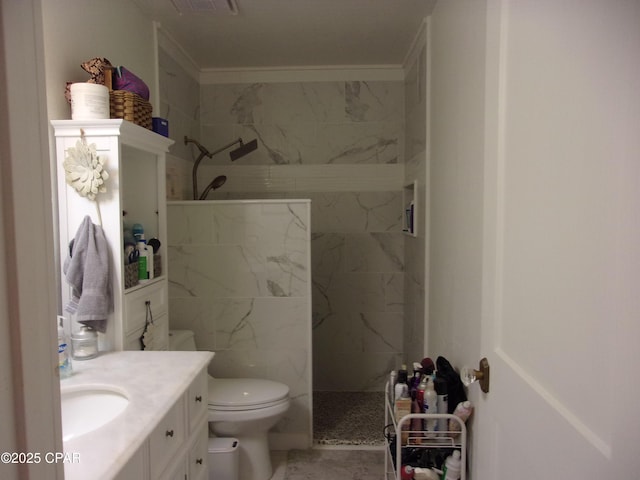 bathroom with vanity, tiled shower, and toilet