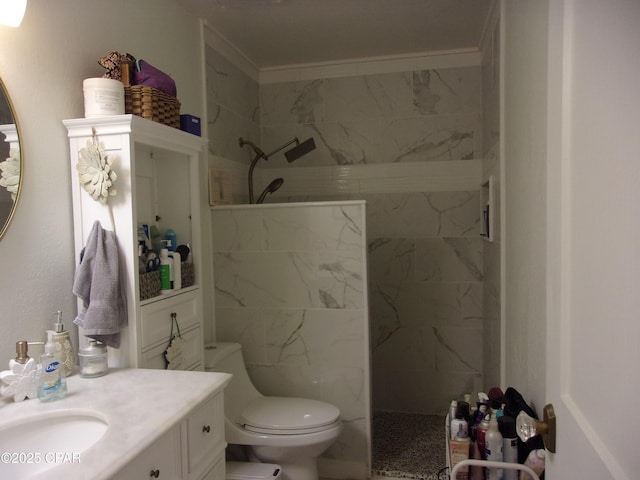 bathroom featuring vanity, ornamental molding, toilet, and tiled shower