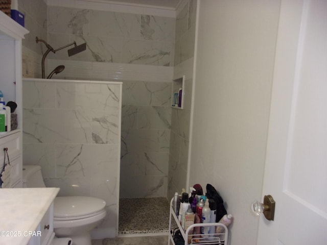 bathroom featuring vanity, tiled shower, and toilet