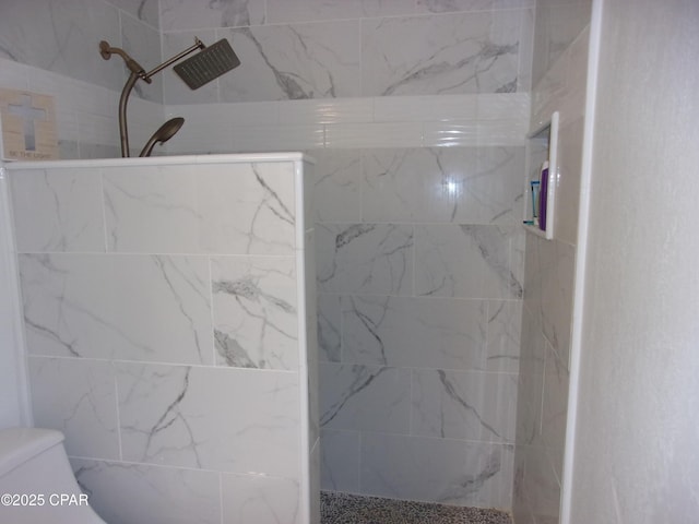 bathroom with a tile shower and toilet