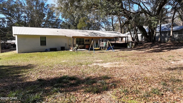 rear view of property featuring a yard and a playground