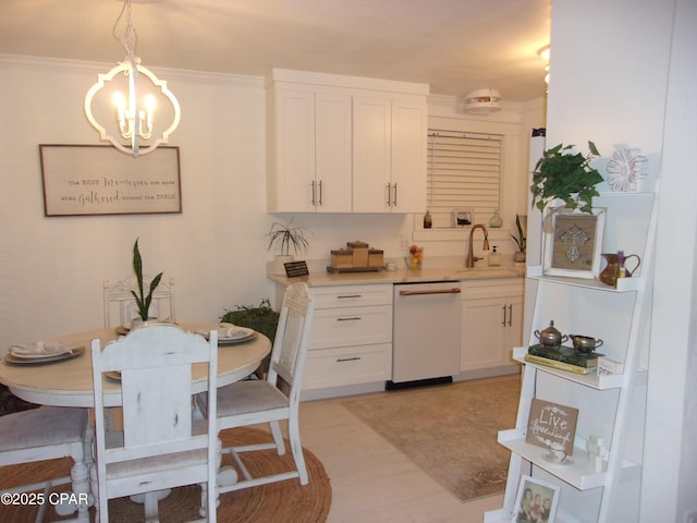 kitchen with dishwasher, a chandelier, pendant lighting, white cabinets, and sink