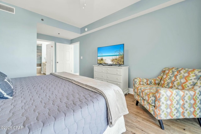 bedroom with ceiling fan, light hardwood / wood-style floors, and connected bathroom