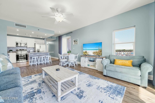 living room featuring ceiling fan and light hardwood / wood-style flooring