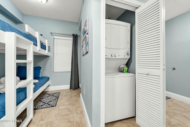 washroom with stacked washer and dryer and light tile patterned flooring