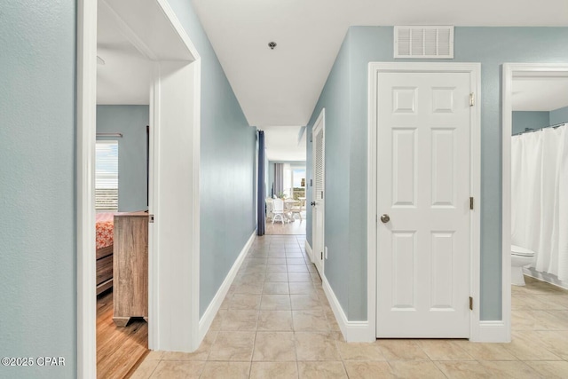 hallway with a wealth of natural light and light tile patterned floors