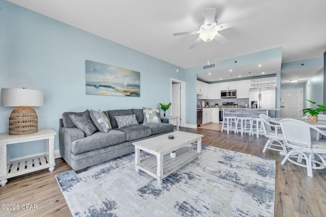 living room with ceiling fan and light hardwood / wood-style flooring