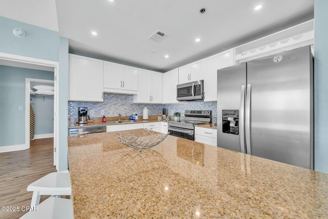 kitchen featuring sink, white cabinetry, light stone counters, and appliances with stainless steel finishes