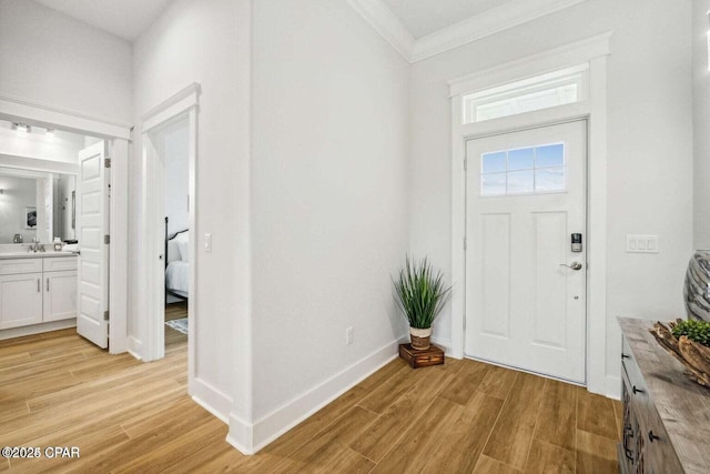 foyer entrance with ornamental molding, light hardwood / wood-style flooring, and sink