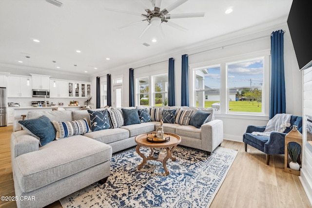 living room with ornamental molding, ceiling fan, and light hardwood / wood-style flooring